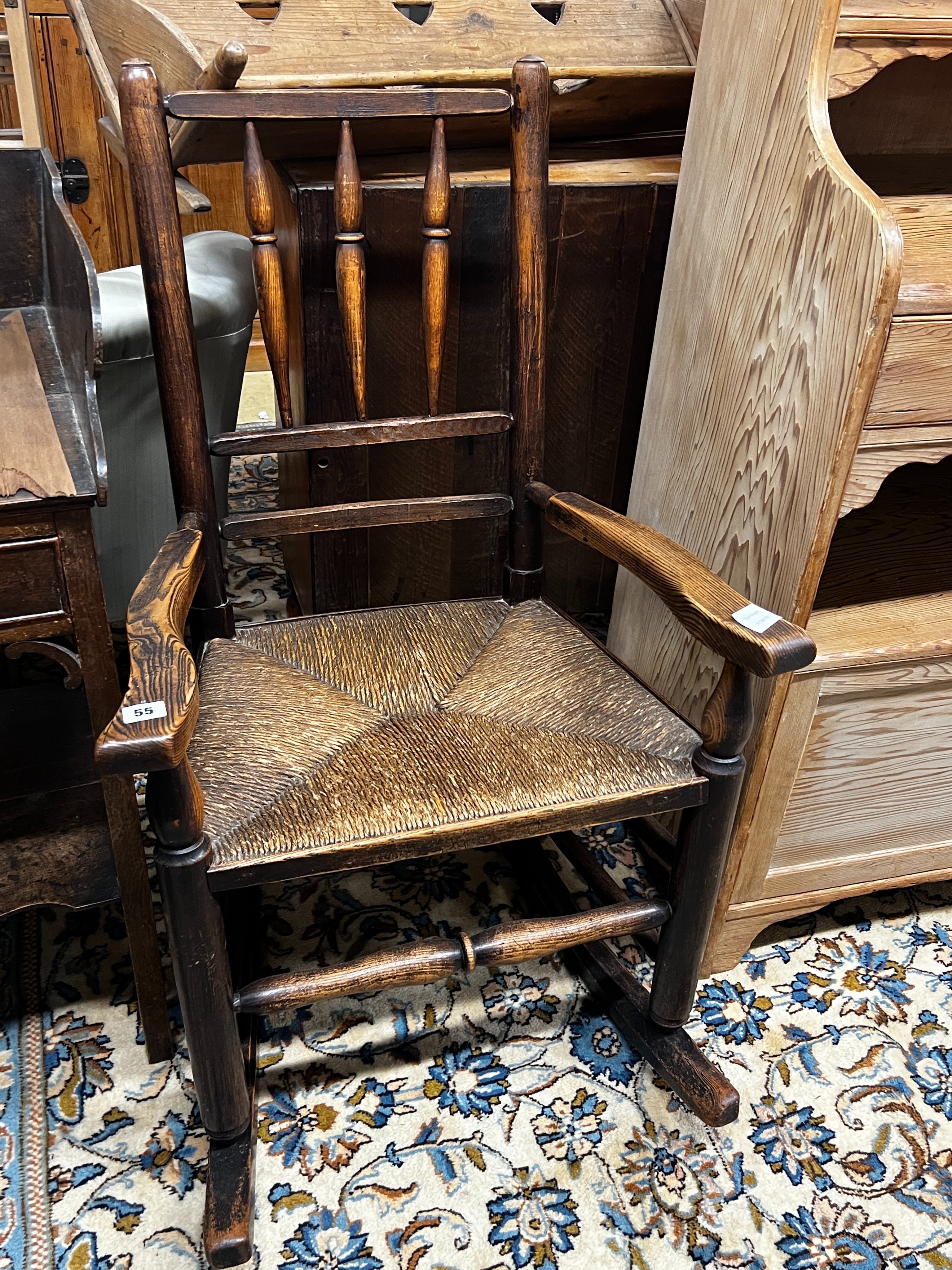 An early 19th century ash rush seat spindle back rocking chair, width 60cm, depth 46cm, height 94cm